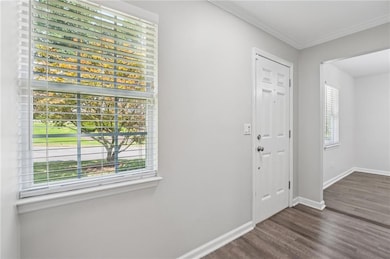 Foyer featuring dark wood-style flooring and ornamental molding