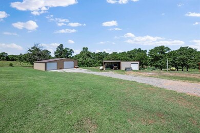 View of green lawn featuring an outbuilding, a detached garage, and driveway