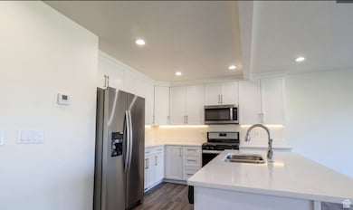 Kitchen with stainless steel appliances, light countertops, white cabinets, and recessed lighting