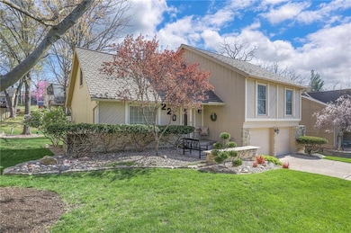 View of front of home with a garage, stone siding, a front lawn, a shingled roof, and concrete driveway