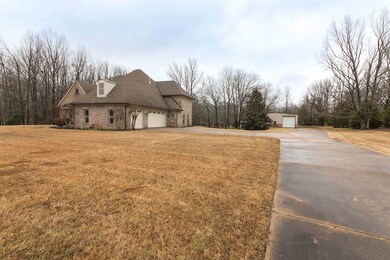 The home features a long concrete driveway with pl