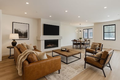 Living room featuring recessed lighting, light wood-style floors, a chandelier, and a glass covered fireplace