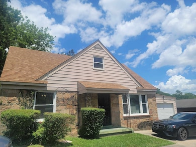 Bungalow-style house featuring an attached garage, stone siding, and a shingled roof