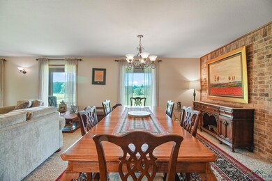 Dining space with a chandelier, light carpet, and brick wall