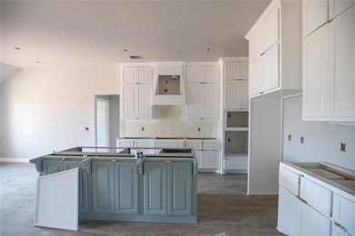 Kitchen with a center island, white cabinetry, dark wood-style floors, and vaulted ceiling