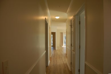 Hall with light wood finished floors and crown molding