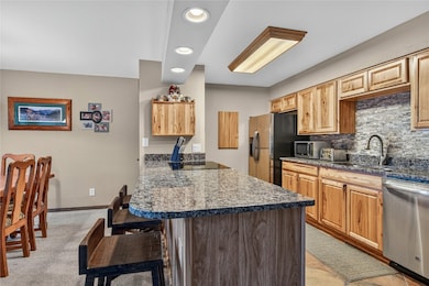 Kitchen featuring recessed lighting, a kitchen bar, stainless steel appliances, and decorative backsplash