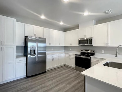 Kitchen featuring appliances with stainless steel finishes, white cabinets, dark wood finished floors, recessed lighting, and light stone counters