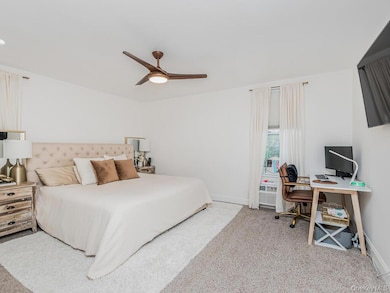 Bedroom featuring light carpet, ceiling fan, and a desk