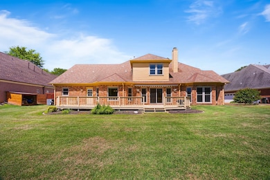 Rear view of house with a huge deck that overlooks a serene lake.