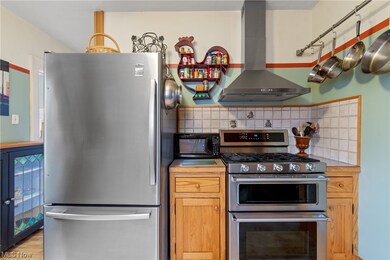 Kitchen with tasteful backsplash, light laminate flooring, stainless steel appliances, range hood