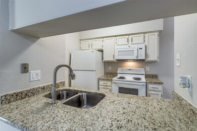 Kitchen featuring white cabinetry, light stone cou