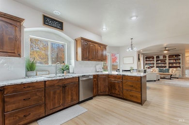 Kitchen featuring decorative light fixtures, light stone counters, dishwasher, ceiling fan, and light wood-style flooring