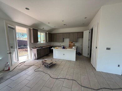 Kitchen featuring vaulted ceiling, a kitchen island, wood finish floors, recessed lighting, and dark brown cabinets