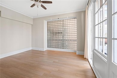Empty room featuring ceiling fan, crown molding, and light wood finished floors