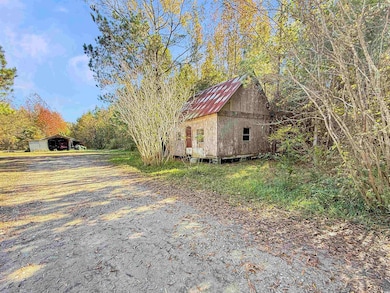 View of property exterior featuring an outbuilding, driveway, a metal roof, and a carport
