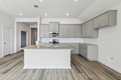 Kitchen with gray cabinetry, appliances with stai