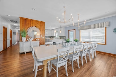 Dining room with ornamental molding, a chandelier, plenty of natural light, baseboards, and wood finished floors