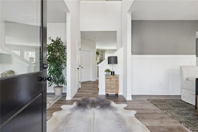 Entrance foyer with wood finished floors, a wainscoted wall, and a decorative wall