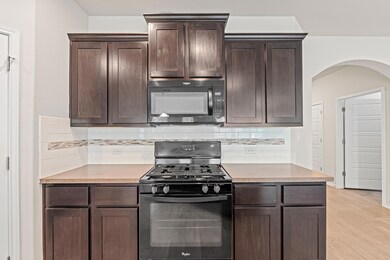 Kitchen featuring black appliances, arched walkwa