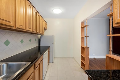 Kitchen featuring open shelves, decorative backsplash, white appliances, and light tile patterned floors