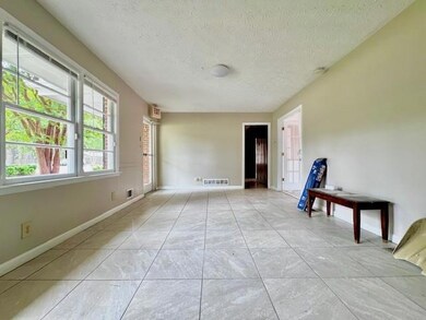 Empty room with a textured ceiling and light tile patterned flooring