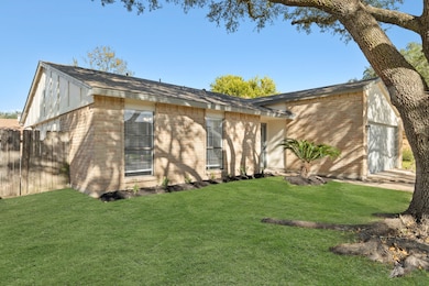 THIS VIEW HIGHLIGHTS THE BRICK FACADE, AND A LARGE SHADE TREE PROVIDING NATURAL COVER OVER THE MANICURED LAWN.