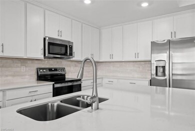 Kitchen featuring decorative backsplash, white cabinets, and stainless steel appliances