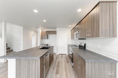 Kitchen featuring modern cabinets, appliances with stainless steel finishes, light wood-style flooring, an island with sink, and recessed lighting