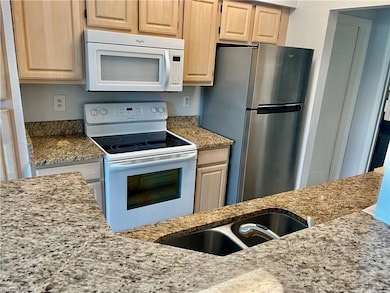 Kitchen featuring light stone counters, light brow