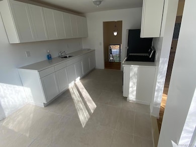 Kitchen featuring white cabinets, light tile patterned flooring, stainless steel appliances, and hanging light fixtures