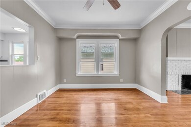 Unfurnished living room featuring a fireplace, ceiling fan, light wood-type flooring, and crown molding