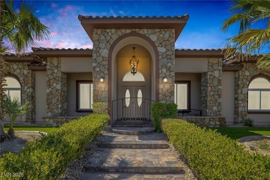 Exterior entry at dusk featuring covered porch, stucco siding, stone siding, and a tile roof