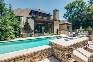 The exquisitely landscaped backyard has newly installed, dramatic lighting, a hot tub and a gorgeous, gunite, Rondo-built custom ozone pool with travertine hardscape patio.