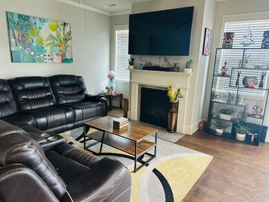 Living area featuring crown molding, wood finished floors, healthy amount of natural light, a fireplace with flush hearth, and baseboards