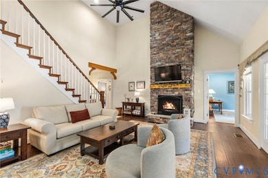 Living room featuring hardwood / wood-style floors, a fireplace, high vaulted ceiling, ceiling fan, and stairway