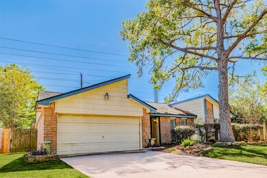 Side-angle view of the front exterior highlighting the spacious driveway, two-car garage, and peaceful residential setting surrounded by mature trees.