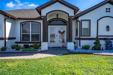 Property entrance with stucco siding, a lawn, french doors, and a shingled roof