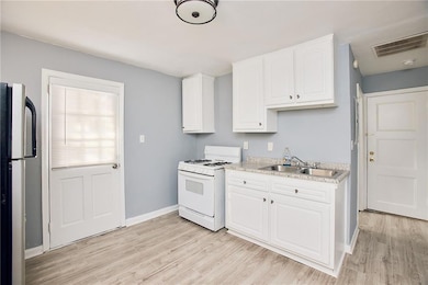 Kitchen featuring white range with gas cooktop, freestanding refrigerator, light wood-style floors, and light countertops