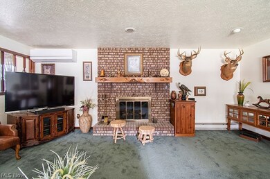Living room featuring a wall mounted air conditioner, a textured ceiling, a fireplace, and dark carpet