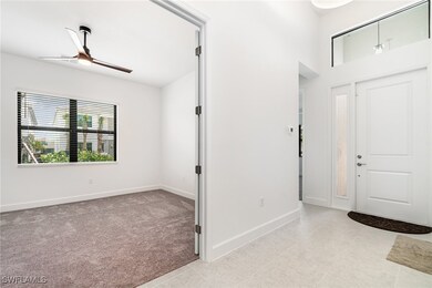 Foyer entrance featuring ceiling fan, baseboards, light tile patterned floors, and light colored carpet