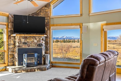 Living room featuring a wood stove, carpet floors, high vaulted ceiling, and a ceiling fan