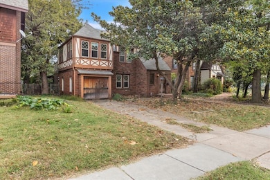 English style home with brick siding, a front yard, a garage, and driveway