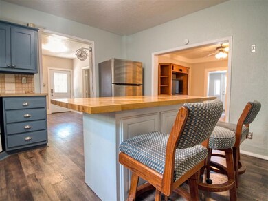 Kitchen with freestanding refrigerator, wooden counters, dark wood-style floors, and blue cabinetry
