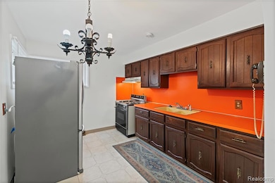 Kitchen with gas stove, freestanding refrigerator, light countertops, decorative light fixtures, and a chandelier