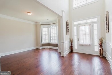 Entrance foyer next to formal living room featuring plenty of natural light, dark wood finished floors, and crown molding