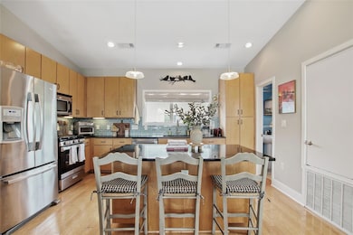 Kitchen with stainless steel appliances, tasteful backsplash, a center island, light wood-style flooring, and recessed lighting
