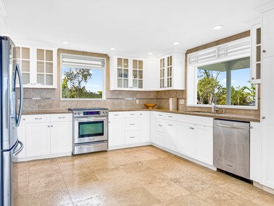 Noche brushed travertine floors in the spacious kitchen with plenty of cabinet storage and views to the coast.