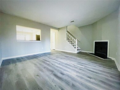 Unfurnished living room with a fireplace with raised hearth, stairway, wood finished floors, and baseboards