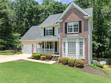 Traditional-style home featuring covered porch, driveway, an attached garage, and roof with shingles